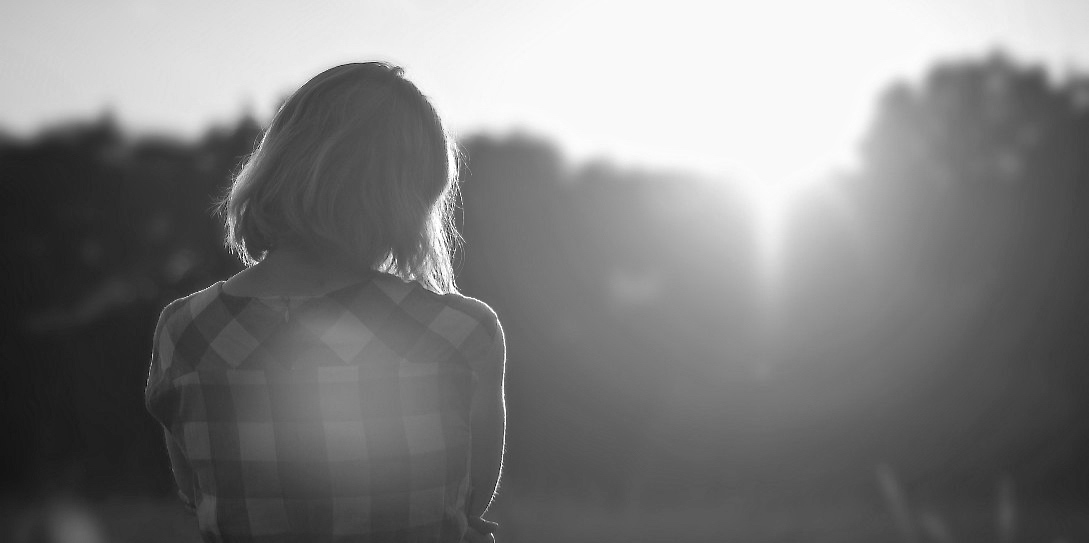 Back of Woman with arms crossed at sunset